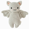 The Cuddle + Kind Baby Limited Edition Grey Bat is a knitted plush toy in the shape of a bat, crafted from light gray Peruvian cotton yarn. It features pink ears, black stitched eyes and mouth, and spread-open wings. A small tag is attached to its side. This hand-knit collectible stands out against the plain white background.