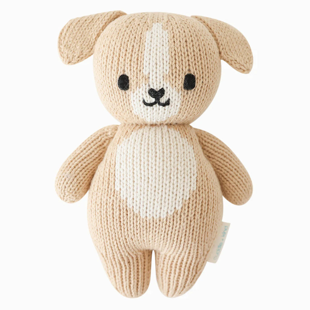 A Cuddle + Kind Baby Puppy designed to look like a cute, beige dog with a white patch on its face and belly, featuring black round eyes and a small nose.
