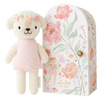 A hand-knit Cuddle + Kind Tiny Charlotte The Dog in a pink dress stands next to a floral patterned, mailbox-shaped packaging labeled "Charlotte the dog".