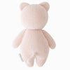 The Cuddle + Kind Baby Kitten (Blush) is a soft, blush pink hand-knit plush made from Peruvian cotton yarn, shown from the back with round ears, a small tail, and outstretched arms—ideal for fans of heirloom dolls and hand-knit baby animals.