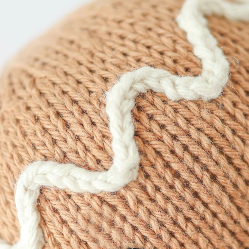 Close-up of the Cuddle + Kind Baby Gingerbread, showcasing a knitted fabric with natural Peruvian cotton yarn in beige and white. The heirloom-quality texture features a tightly knitted beige background complemented by a soft, cozy zigzag pattern in white.