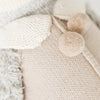 Close-up of Cuddle + Kind Greyson the Penguin, a cotton yarn doll in soft beige and cream with textured details, two fluffy pom-pom buttons, and a ribbed collar, showcasing a cozy handmade look.