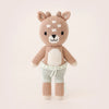 A Cuddle + Kind Tiny Elliott The Fawn, featuring a light brown color with a white belly and face accents, sporting pale green pants, and standing upright against a soft pink background.