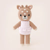 A cute hand-knit toy deer standing upright, featuring a pale brown body, a smiling face, and wearing a cozy white sweater with pink stripes named Cuddle + Kind Tiny Violet The Fawn.