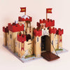 The Lionheart Wooden Castle features red battlements, flags adorned with yellow lions, a functioning drawbridge, and decorative shields. Expertly crafted from sustainable wood for lasting durability, this castle sits on a base painted with stone paths and climbing vines—making it perfect for inspiring imaginative play against a simple background.