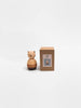 The Sabo Concept Bear Stacker - Beige, a small wooden toy with a round body, stands beside its brown box displaying its image, all set against a plain white background.