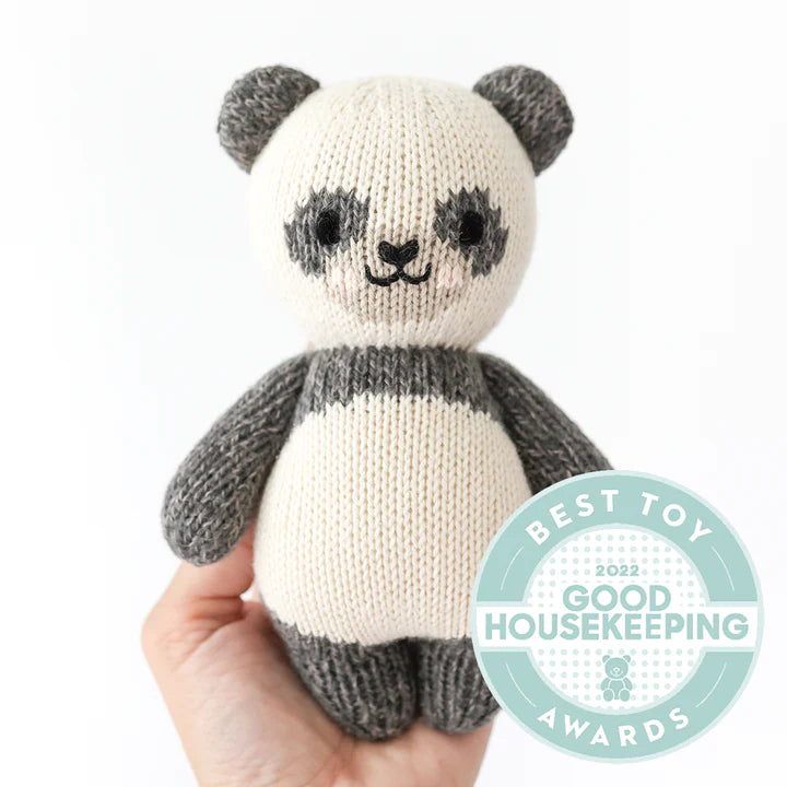 Hand holding a Cuddle + Kind Baby Panda doll with the Good Housekeeping Best Toy Awards 2022 seal in the bottom right corner against a white background.