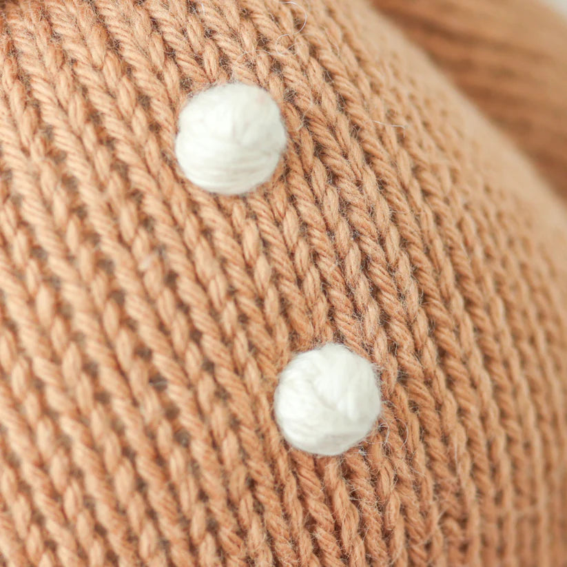 Close-up of the Cuddle + Kind Baby Gingerbread knitted fabric in beige, crafted from natural Peruvian cotton yarn and featuring two small, white, round hand-knit baby animals sewn onto it. The intricately stitched texture highlights its heirloom-quality craftsmanship.