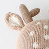 Close-up of a beige hand-knit Cuddle + Kind Elliott the Fawn doll hat with white spots, a soft deer ear, and two antlers on top—crafted from sustainable fair trade materials.