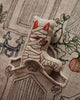 A small, embroidered cat plush wrapped in bandages peeks out from a Coral & Tusk Graveyard Pocket Pillow featuring fabric with garden gate and plant designs.