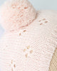 Close-up of the Cuddle + Kind My First Baby (Blush) hat, featuring light pink hand-knit cotton with a large pom-pom, ribbed edge, and openwork diamond pattern. Ships in one week.