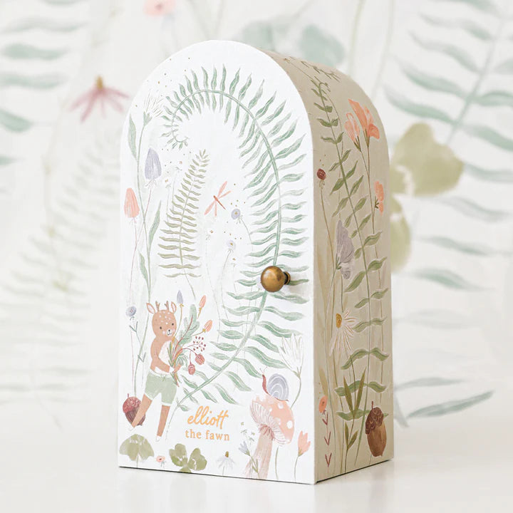 A whimsical children's money box shaped like an arched doorway, decorated with a pastel illustration of plants and a fawn named Cuddle + Kind Tiny Elliott. It also includes tiny dolls and a small gold knob.