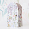 A whimsical Cuddle + Kind Tiny Violet The Fawn mailbox decorated with illustrations of lilac flowers, various other blooms, and a small character, standing on a paintbrush, in a floral setting celebrating the Tiny Violet birthday.