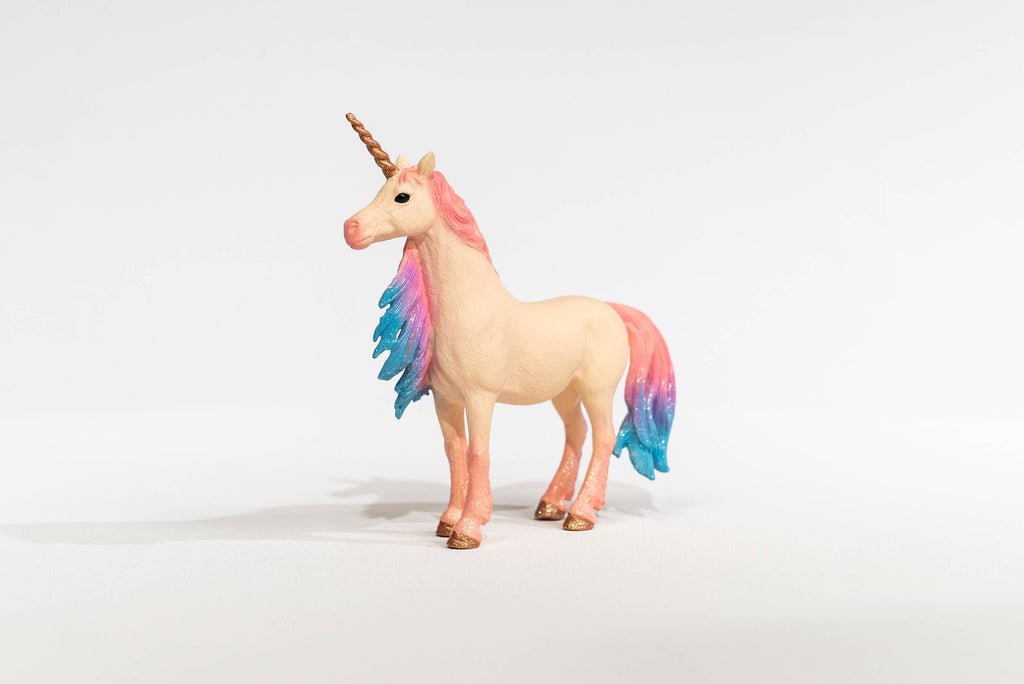 The Schleich Marshmallow Mare Unicorn is a limited edition figurine featuring a golden horn and a pink-and-blue glittery mane and tail. It stands on a white surface against a plain white background, making it a delightful addition to any Schleich unicorns collection.
