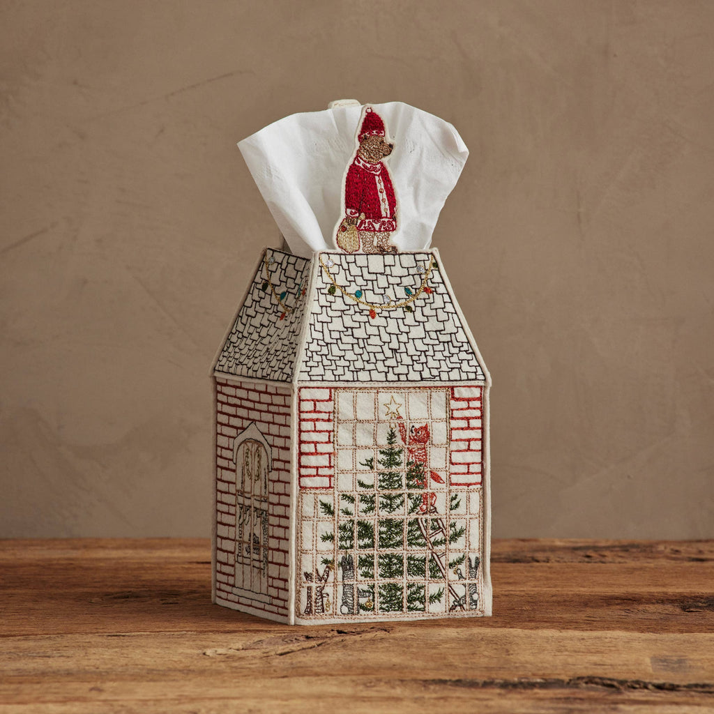 The Coral & Tusk Home for the Holidays Tissue Box Cover is a charming embroidered house-shaped cover featuring festive holiday designs, including a tree in the window and Santa on the roof, perfect for seasonal decor.