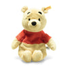 The Steiff Disney's Winnie the Pooh Bear Stuffed Plush Toy, standing at 11 inches, sits upright and showcases its friendly expression with raised eyebrows, black button eyes, and a small black nose. Wearing a red shirt and featuring a manufacturer's tag on its left ear, this Disney plush toy is perfect for any fan.