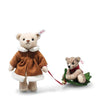 The Steiff Mama Teddy Bear With Child features a mama bear in a brown coat with white trim holding a red leash, leading her child bear on a green sled—ideal for your Christmas display against a white background.