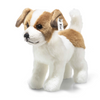 A Steiff Terrie Dog plush with white and brown fur stands on all four legs. This realistic stuffed dog features floppy ears, black eyes, a black nose, and a fabric tag attached to its left ear. The background is plain white.