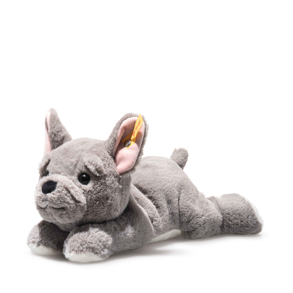 Steiff Brie French Bulldog is a soft, cuddly plush toy with black eyes, a black nose, light pink inner ears, and Steiff's signature yellow tag on its left ear, shown lying down against a white background.