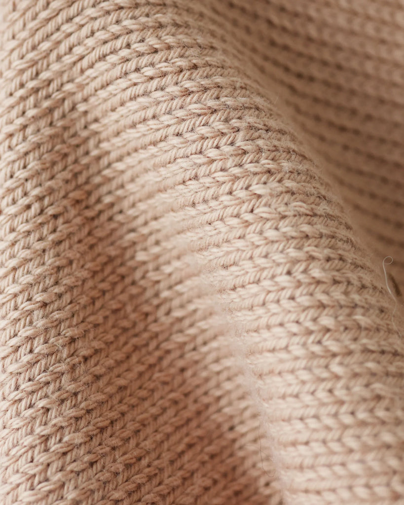 Close-up of the Cuddle + Kind Organic Cotton Baby Fawn Lovey shows its beige, ribbed knit texture and gentle folds, highlighting the detailed weave and soft, heirloom-quality design.