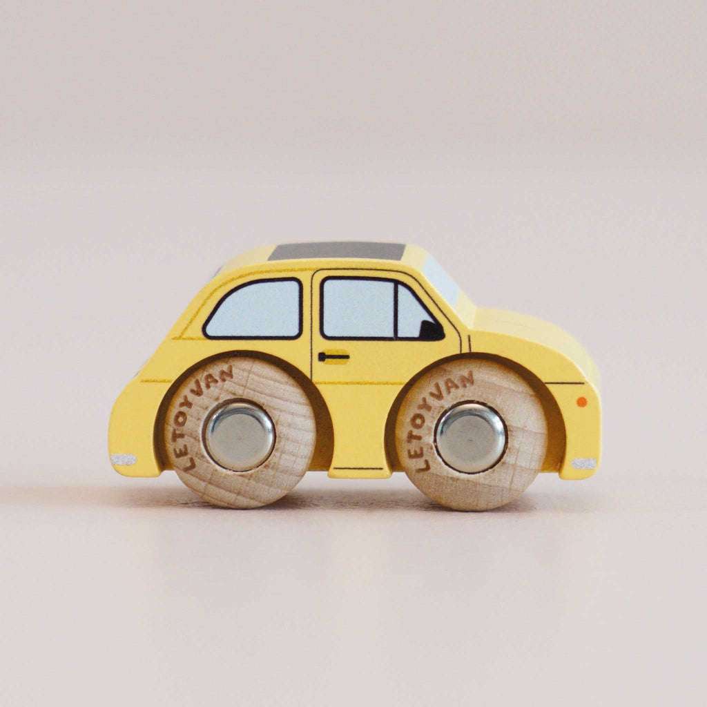 A classic No. 10 GT60 Fifi miniature yellow wooden toy car, made in England, featuring round wooden wheels, black windows, and simple details, photographed on a plain light background.