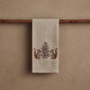 The Coral & Tusk Chipmunks with Pinecone Tea Towel in beige linen hangs on a wooden rod and features a woodsy design with two brown chipmunks facing a symmetrical, ornate pinecone tree pattern in the center.