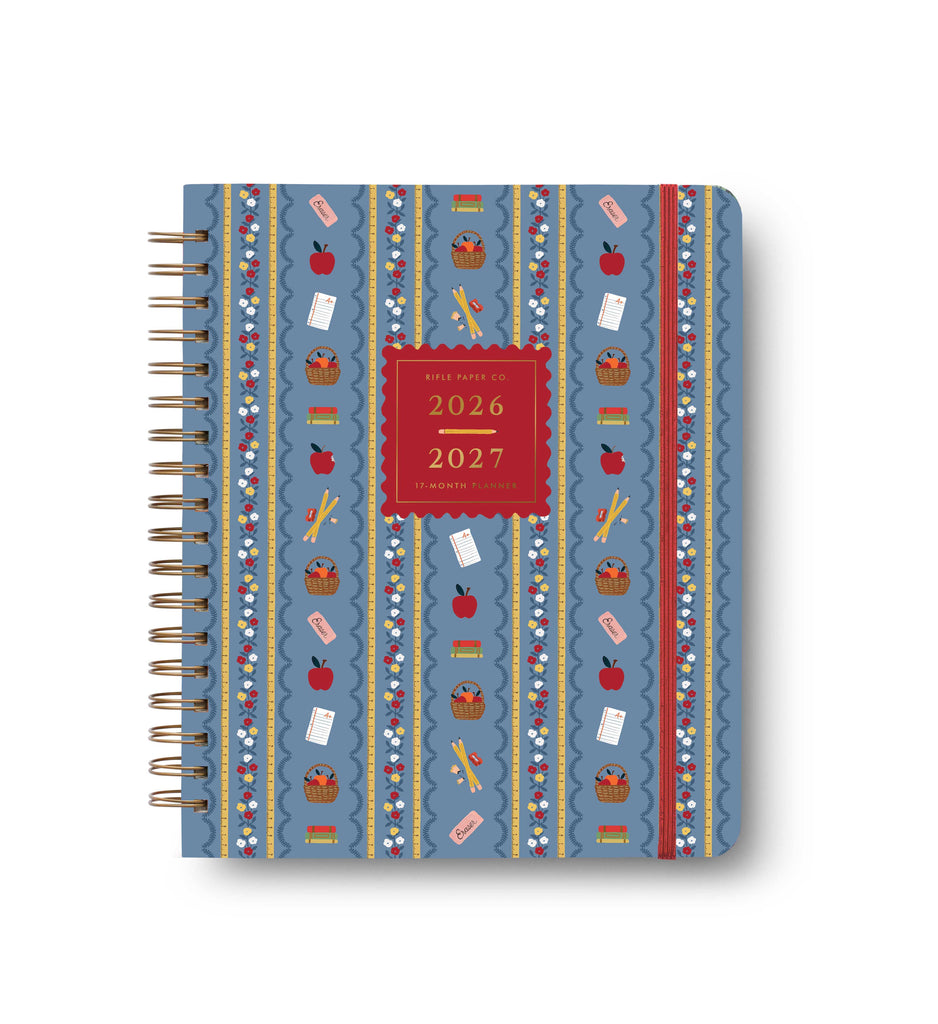 The 2027 Schoolhouse 17-Month Academic Hardcover Spiral Planner is a large spiral-bound planner for 2026-2027, featuring a vibrant blue cover adorned with apples, books, pencils, erasers, and lined paper arranged in vertical rows.