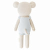 Cuddle + Kind Beatrice The Mouse - Periwinkle is a handmade beige knit stuffed animal with round ears in light blue overalls, crafted from sustainable fair trade materials and hypoallergenic polyfill. The back view shows its tail and arms.
