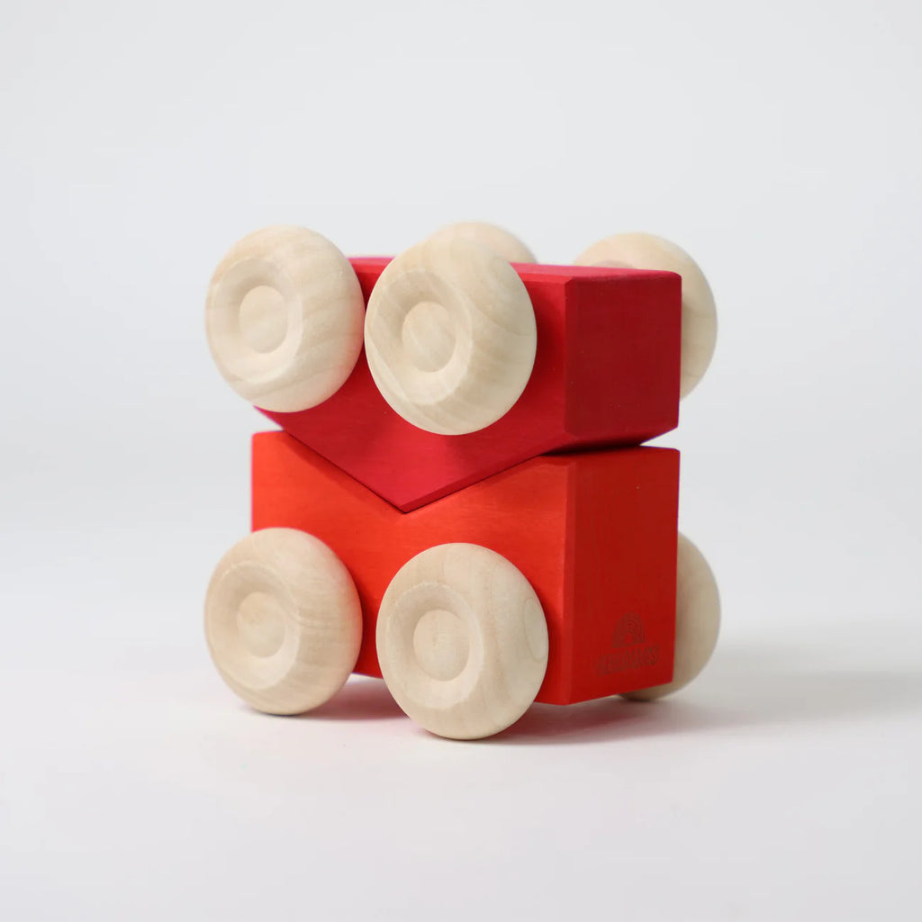 Two red wooden toy blocks with natural wood wheels are stacked one on top of the other against a white background. These stacking toys resemble simplified cars, similar to Grimm's Stacking Cars - Red (coming soon).
