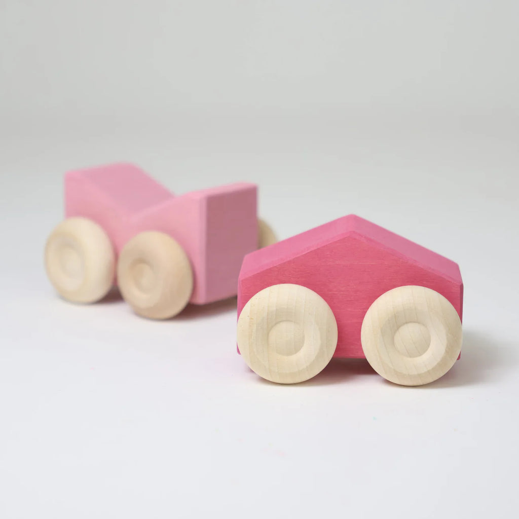 Two Grimm's Stacking Cars - Pink, featuring natural wood wheels, are displayed on a white surface. These charming wooden stacking toys spark creativity and make playtime extra special.