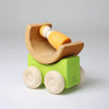 Grimm's Stacking Cars - Green features a wooden toy car with a green rectangular base, four round wheels, and a semi-circular cradle holding an orange and white peg doll—ideal for color matching and stacking play. Coming soon!.