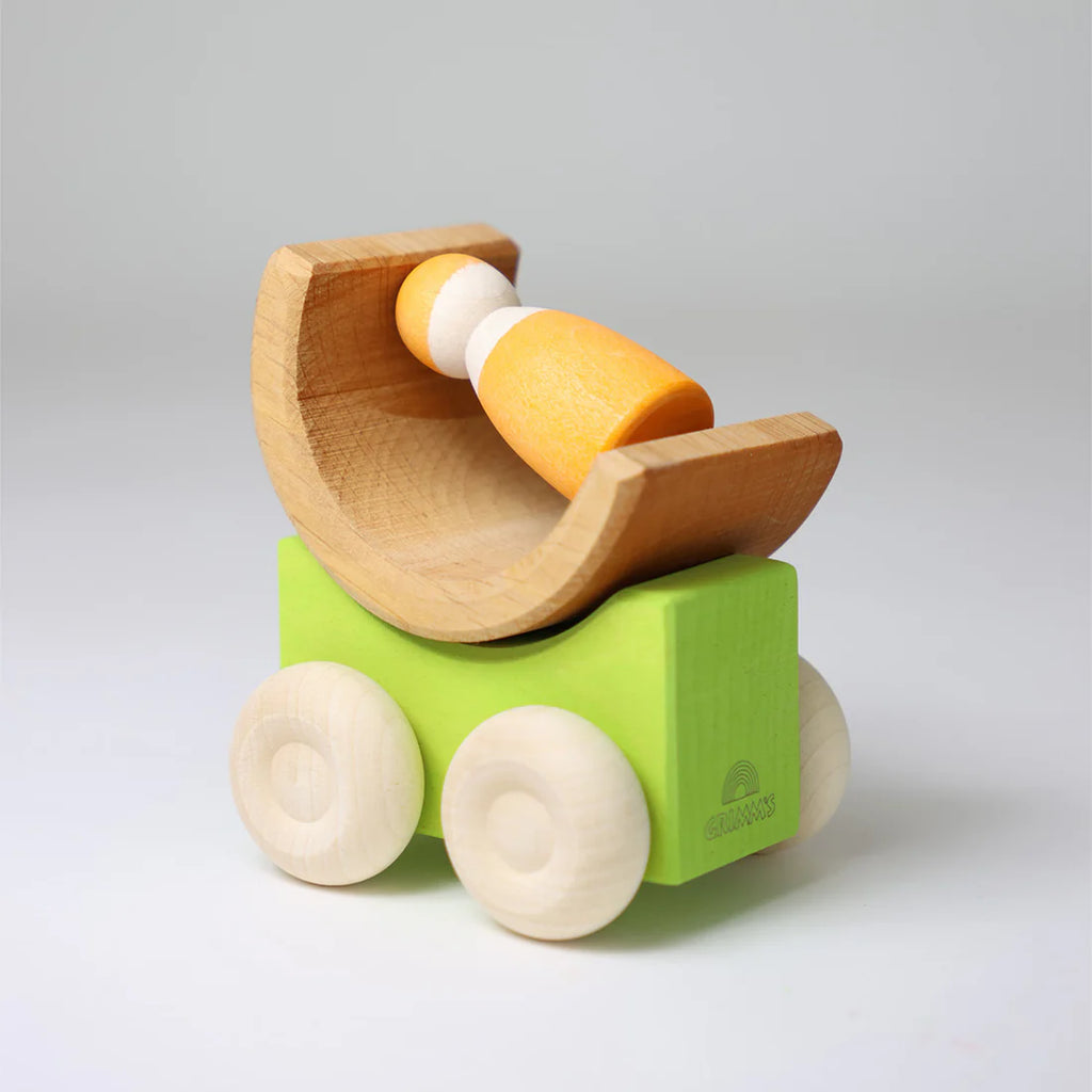 Grimm's Stacking Cars - Green features a wooden toy car with a green rectangular base, four round wheels, and a semi-circular cradle holding an orange and white peg doll—ideal for color matching and stacking play. Coming soon!.