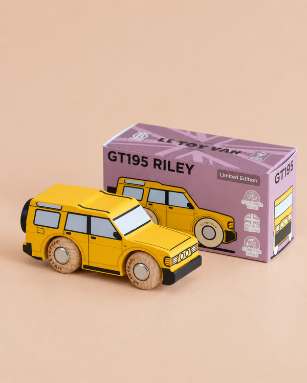 A yellow off-road toy SUV with wooden wheels is displayed in front of its purple box labeled “No. 35 GT195 Riley | Made in England” on a beige background. The box features an illustration matching the adventure vehicle.