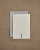 The Coral & Tusk Fox Mama Card—a white textured keepsake with a small tree logo and "CORAL & TUSK" at the bottom—comes atop a gray envelope on a light brown surface, making it an ideal gift for new parents.