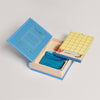 Scrabble for Juniors Vintage Bookshelf Edition board game with a grid board, a teal drawstring pouch, letter tiles, and red tokens stored inside a book-shaped box.