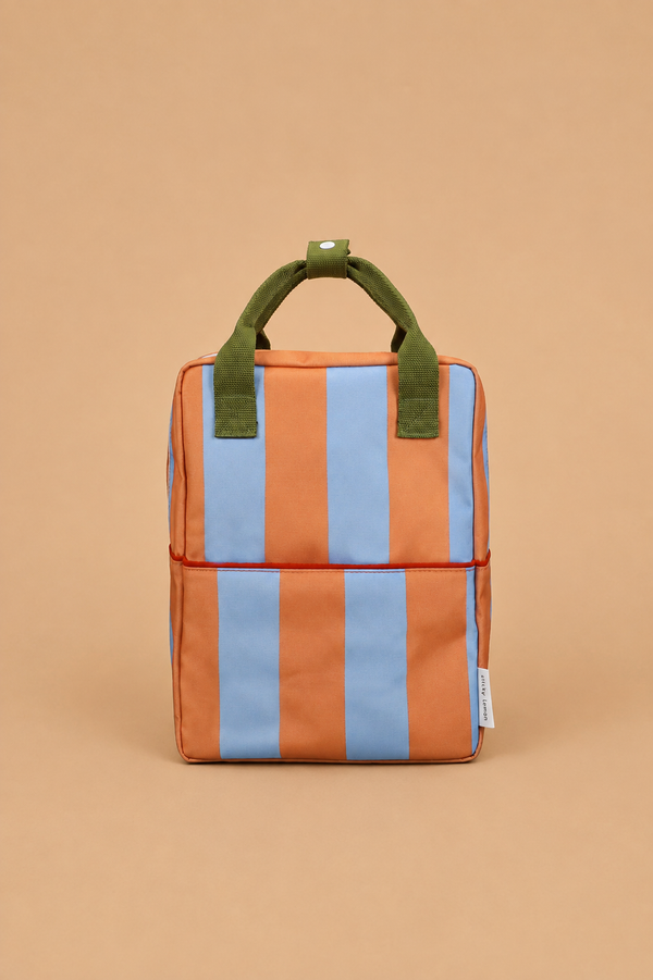 The Sticky Lemon Backpack Medium | Stripes | Cloud Blue + Maple Whirl is a small rectangular backpack featuring vertical orange and blue stripes, green handles, and a white tag, crafted from recycled PET bottles with a waterproof lining and displayed on a light brown background.