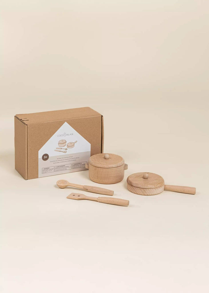 The Wooden Pots and Pans Playset (6 Pcs) features two wooden pots with lids, a spatula, and a spoon—ideal for inspiring imaginative play and creativity in little chefs. This kids kitchen playset is attractively displayed in front of a brown cardboard box with a white label.