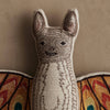 The Coral & Tusk Bat Surprise Doll features embroidered facial details, large ears, and vibrant orange, red, and yellow patterned wings, set against a plain beige background.