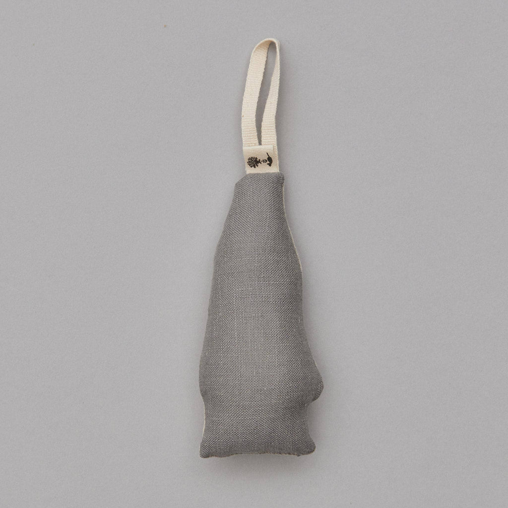 A pale looped strap holds a North Pole Bear Ornament against a light gray background, featuring a gray fabric pouch shaped like a human nose, exuding Santa Bear's whimsical charm.