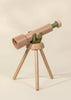 The Wooden Tripod Telescope – 15x Zoom, with a green accent, stands on a classic three-legged wooden base against a beige backdrop—ideal for inspiring imaginative pretend play adventures.