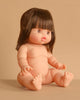 The Minikane Baby Doll (13") - Jeanne, an adorable anatomically correct nude doll with straight brown hair and bangs, sits on a beige surface against a matching background. Made in Spain. Clothing sold separately.