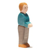 An Ostheimer Father, Blue Sweater figurine of a person standing. The figure has light brown hair and is wearing a blue shirt and gray pants. With simple, painted facial features and a minimalist design, it captures the essence of handcrafted wooden toys from Germany. The person is shown in profile view facing left.