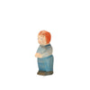 An Ostheimer Toddler figurine of a person with short, red hair. The figurine is dressed in blue pants and a light blue shirt, standing upright with arms folded. Made from sustainably sourced materials and inspired by Ostheimer toys, it features a plain white background.