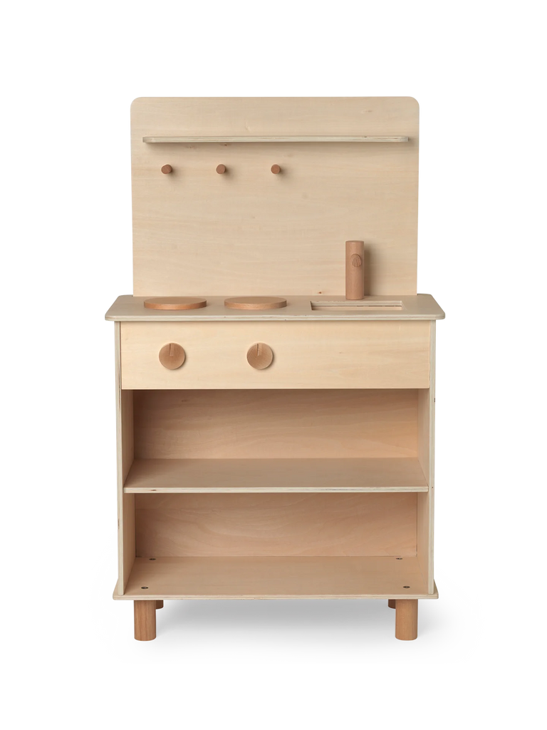 A Ferm Living Toro Play Kitchen set featuring a stove top, oven, and storage shelves, with simple knobs and accessories, against a soft, striped background.