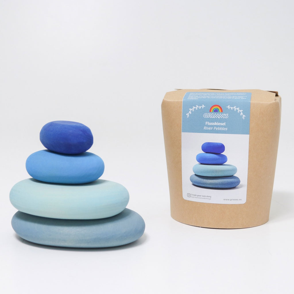 A stack of five smooth, flat, gradient blue stones is shown next to a cardboard container labeled "River Pebbles Stacker." The packaging, adorned with the brand logo and a rainbow, features an image of the same stone stack. These organic stone shapes vary in size, with the largest at the bottom.