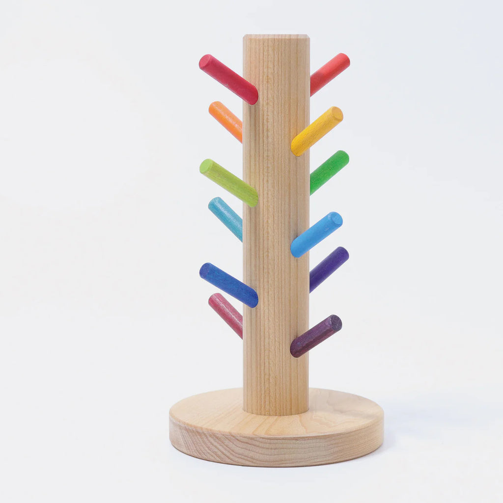 Grimm's Sorting Helper for Building Rings - Rainbow features a light-colored wooden stand with a natural oil finish and colorful pegs spiraling around the center post. Ideal for sorting games, each peg is painted in vibrant rainbow hues.