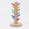 Grimm's Sorting Helper with Building Rings Set features a wooden base and central post, with colorful red, orange, yellow, green, blue, and purple pegs spiraling diagonally to boost fine motor skills. Inspired by Grimm's Building Rings.