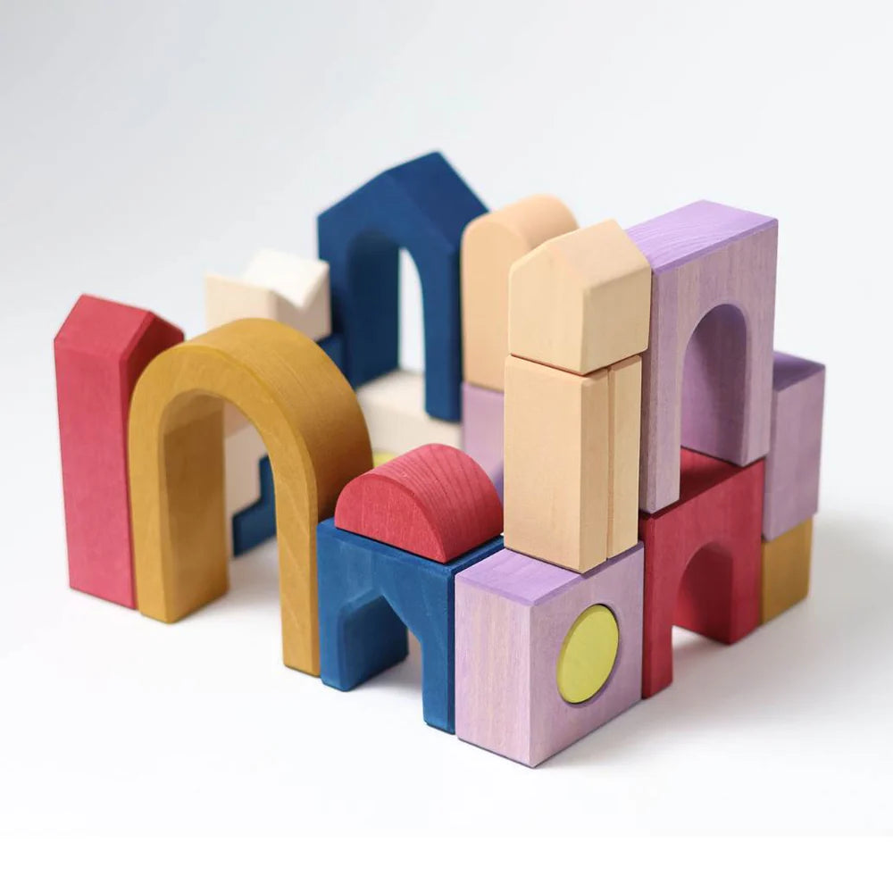 An abstract structure made with Grimm's Panorama Building Set—colorful wooden arches, rectangles, squares, and curved blocks—from the Tiny Art Collection stands on a plain white background.