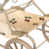 Close-up view of a beige fabric seat with a cherry pattern, mounted on a metal frame, part of a Doll Pram - Glitter Cherry.