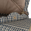 Close-up of a beige and blue checkered fabric with a small daisy-shaped embroidery on a Doll Pram - Blue Checkered quilted printed fabric, possibly on a piece of clothing or a textile accessory.